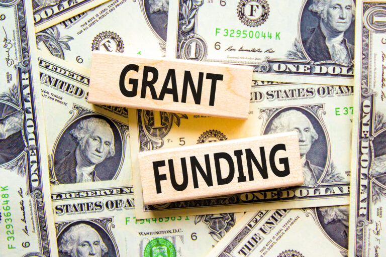 Grant funding symbol. Concept words Grant funding on wooden blocks. Beautiful background from dollar bills. Business and grant funding concept. Copy space.